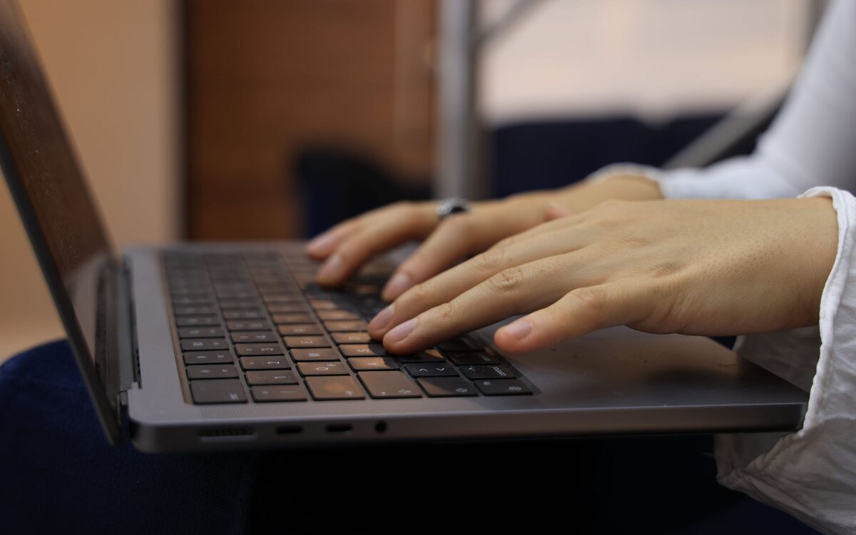 Hands typing on a laptop keyboard